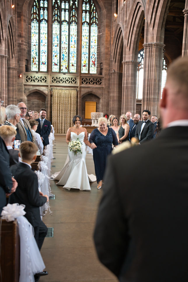 The bride is walked down the aisle by her mother to meet her future husband at St George's Church, London Road, Stockport