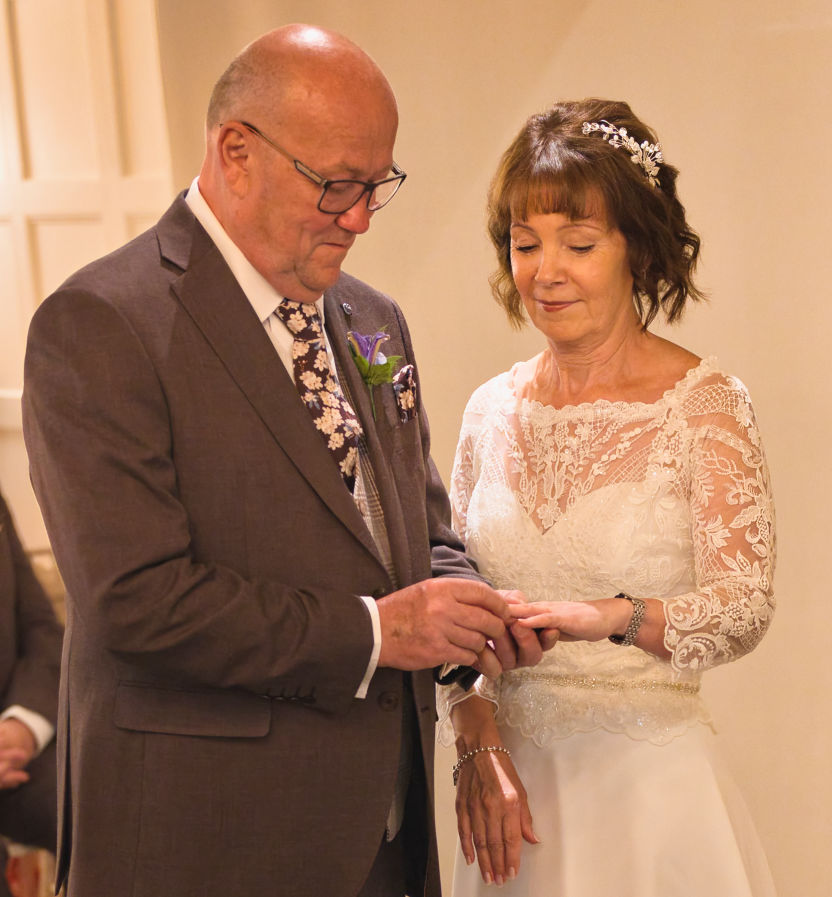 The groom put the wedding ring on the brides finger at Stanneylands in  Wilmslow 