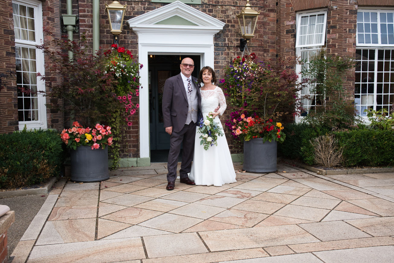 A bride and groom stand out there the entrance of the Stanneylands Hotel Winslow